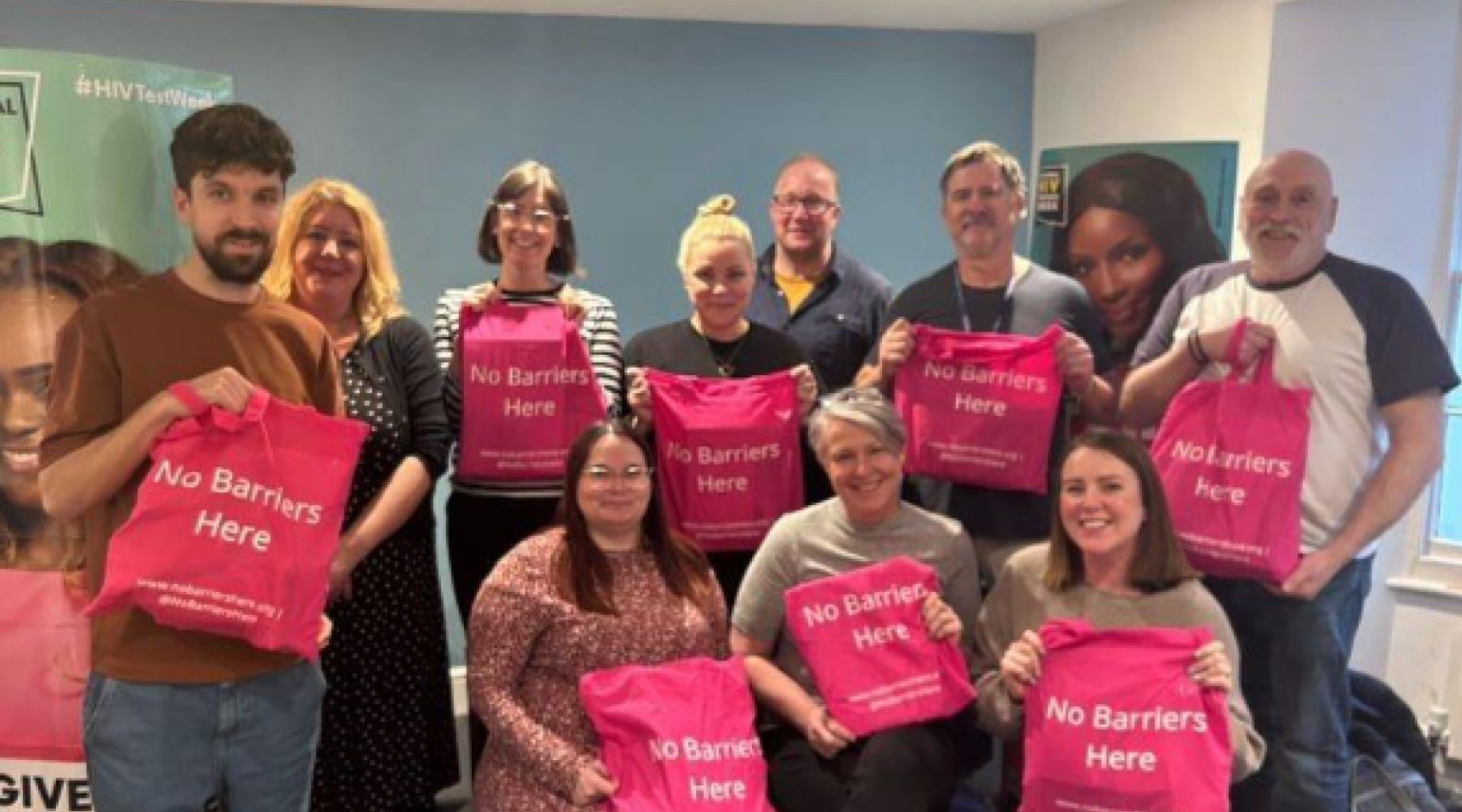 Terrence Higgins Trust group photo, with everyone holding pink 'No Barriers Here' bags