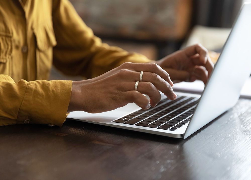 A closeup of a person's hands as they type on a laptop.