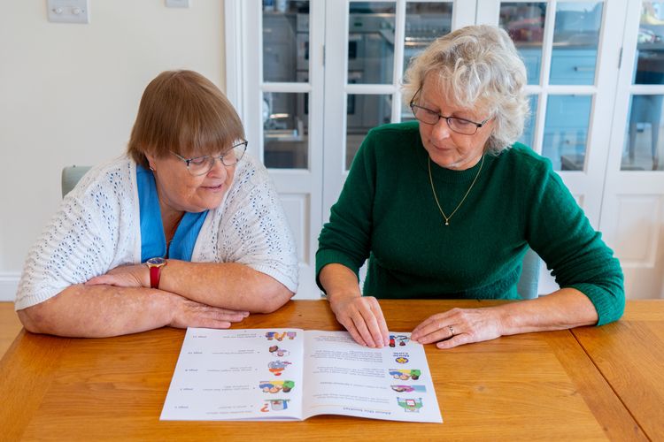 Two women read an Easy Read booklet.