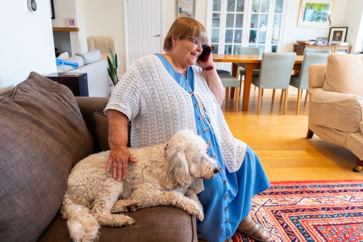 A woman speaks on the phone and pets her dog.
