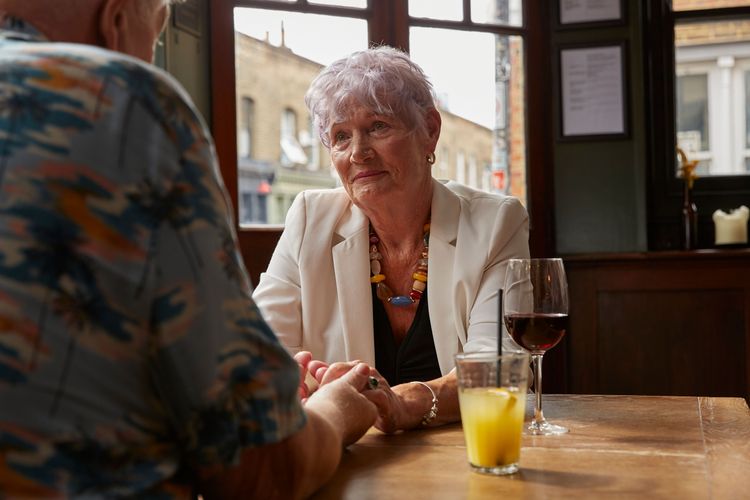A woman holding someone's hands across the table