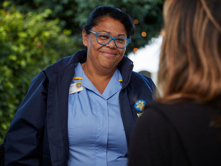 A Marie Curie Nurse smiles as she speaks to a woman 