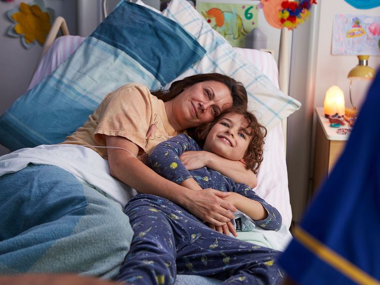 Patient parent at home with their child being looked after by a Marie Curie Nurse 