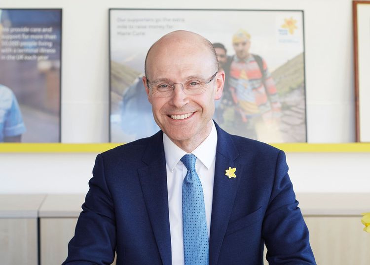 CEO Matthew Reeds smiles as he poses for a photograph. He's wearing a suit with a daffodil pin on the lapel.