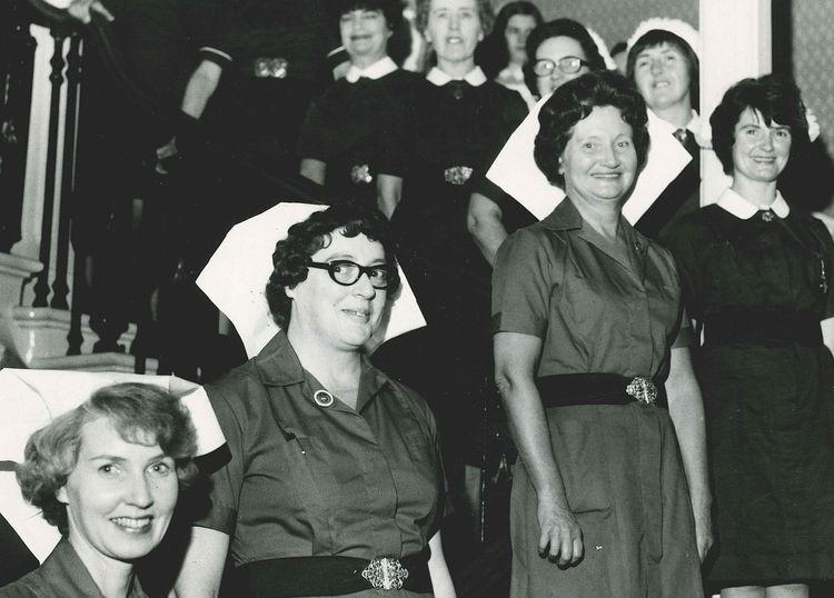 An archival photograph of Marie Curie Nurses smiling as they pose for a photograph