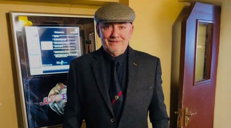 Jim Dunn dressed in a suit and flat cap