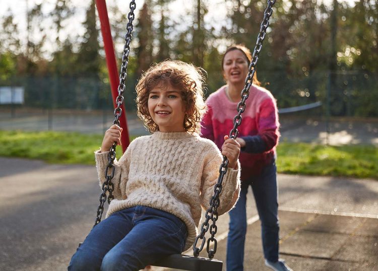 Parent pushing a child on a swing