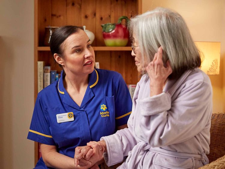 Marie Curie Nurse caring for a patient at home in their living room