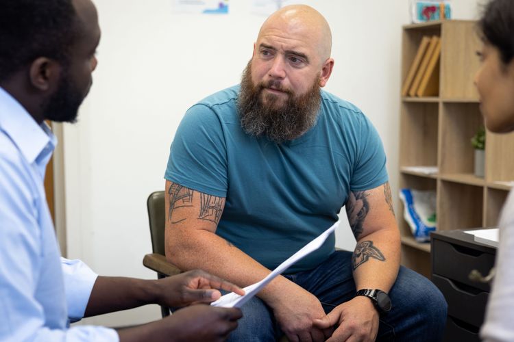 a man sits facing a doctor who is sharing results with him. He looks distressed.
